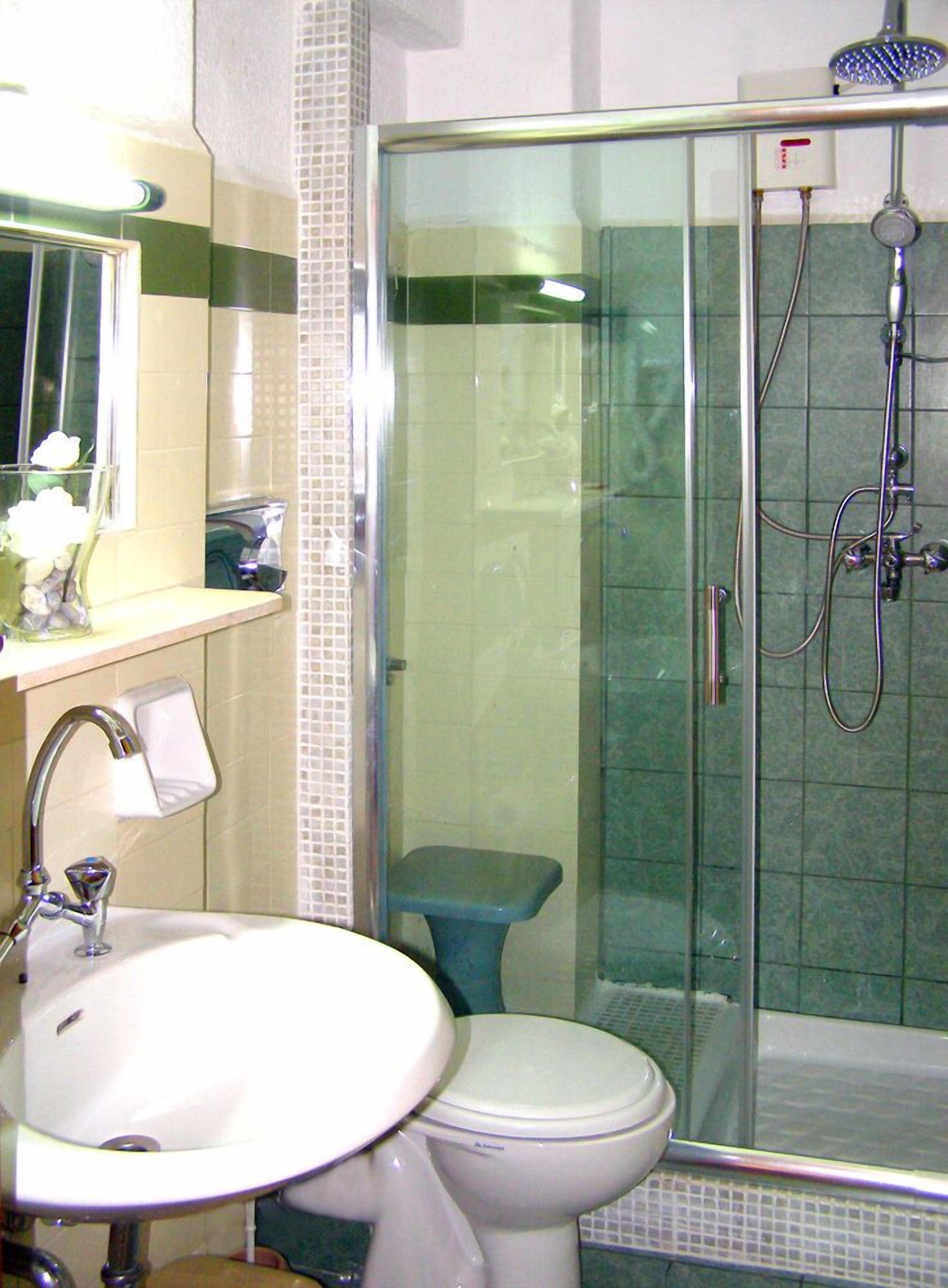 Een badkamer met een douche met glazen wand, een wastafel en een toilet.