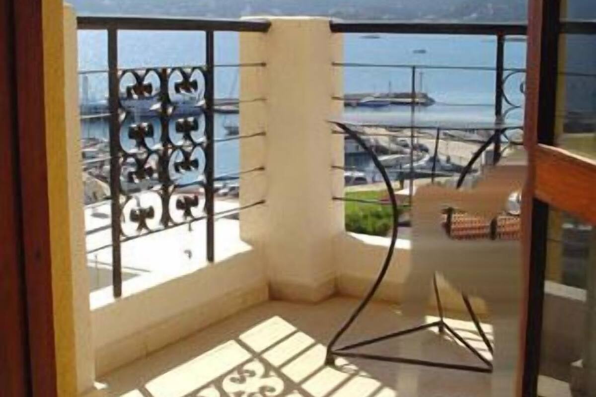 Un balcon avec une balustrade en métal, une petite table et une chaise.