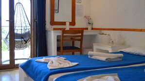 Een hotelkamer met een bed, een bureau, een stoel, een hangstoel en een raam met uitzicht.
