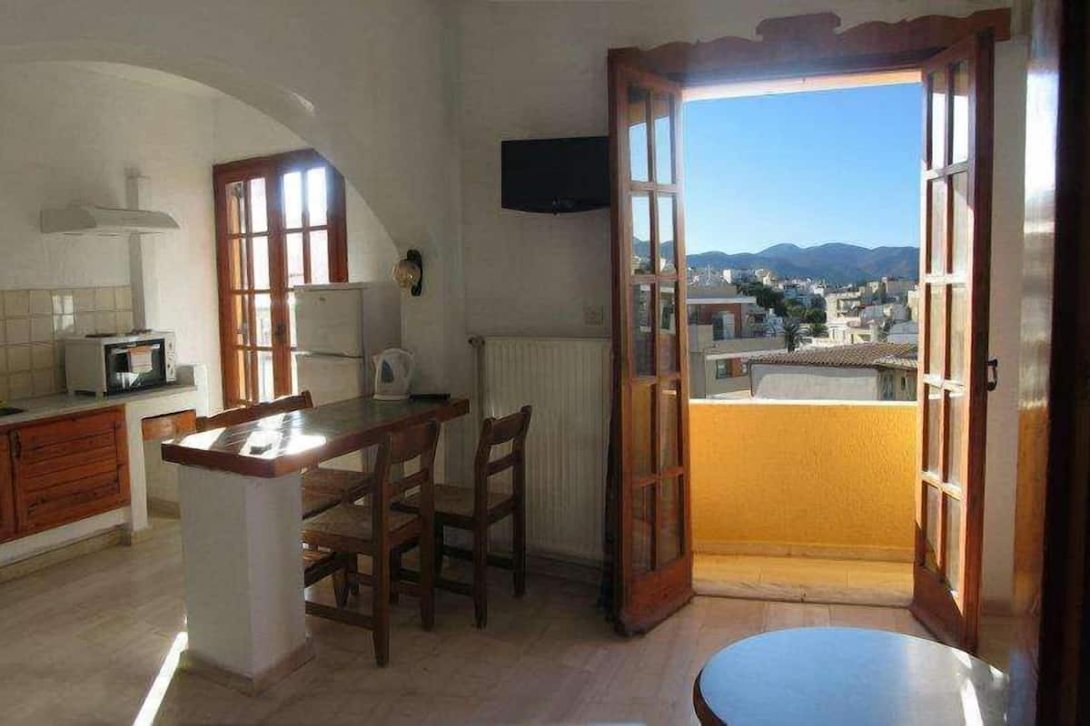 Une cuisine avec un coin repas, une vue sur la ville et un balcon.