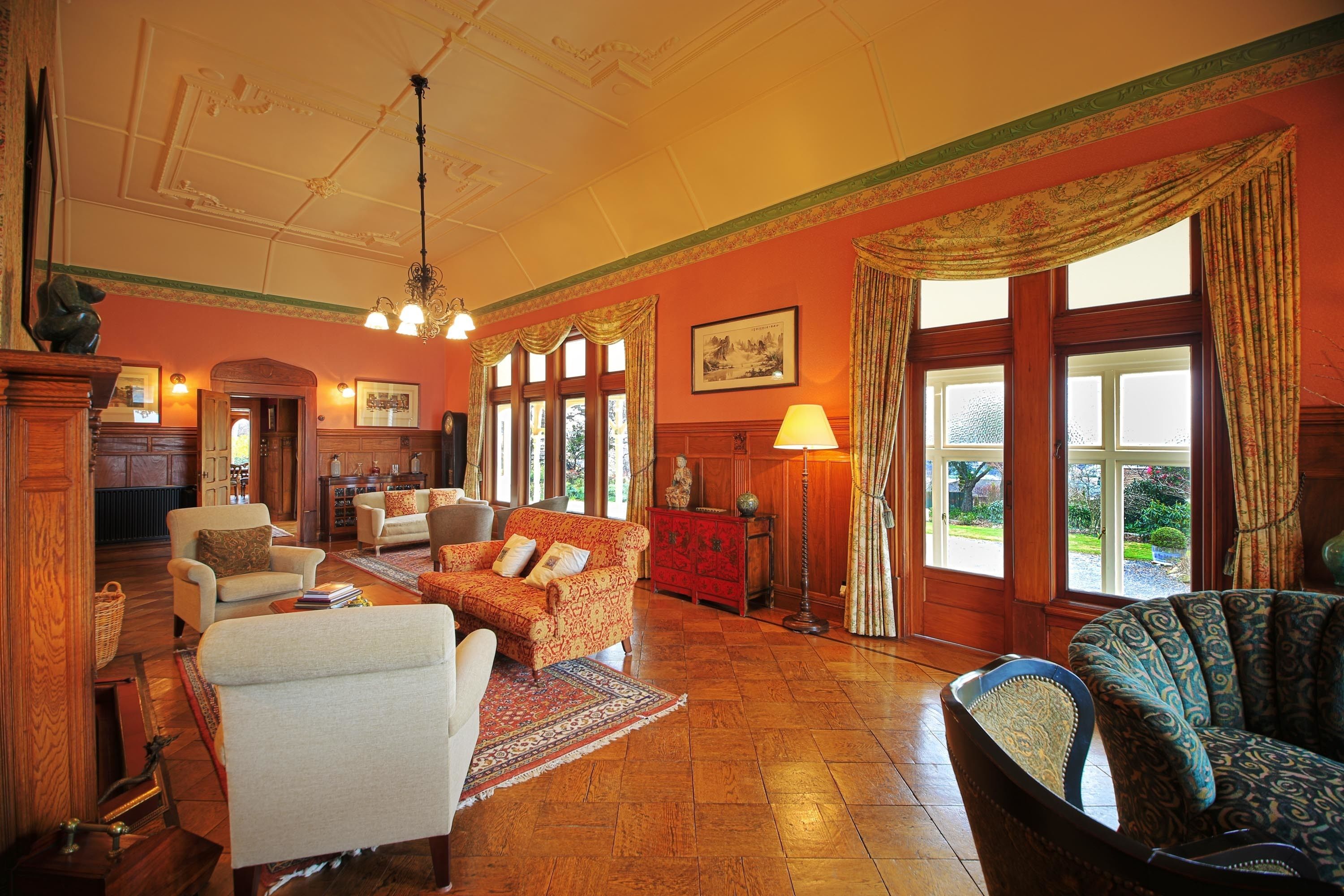 A spacious living room with a fireplace, multiple seating options, and large windows offering a view of the outdoors.