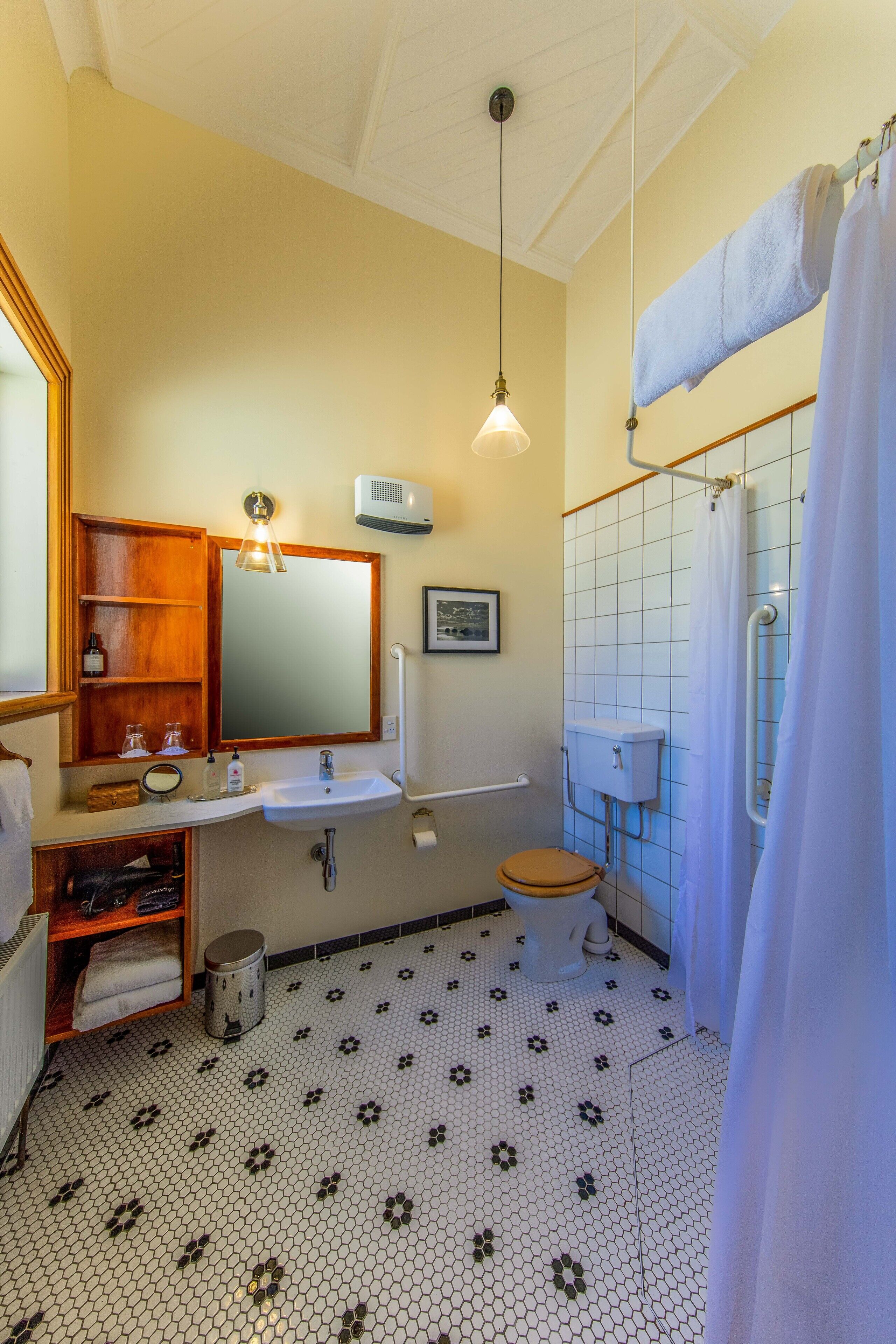 A bathroom with a white sink, wooden vanity, and a shower with a white curtain.