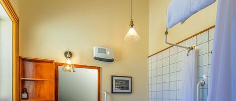 A bathroom with a white sink, wooden vanity, and a shower with a white curtain.