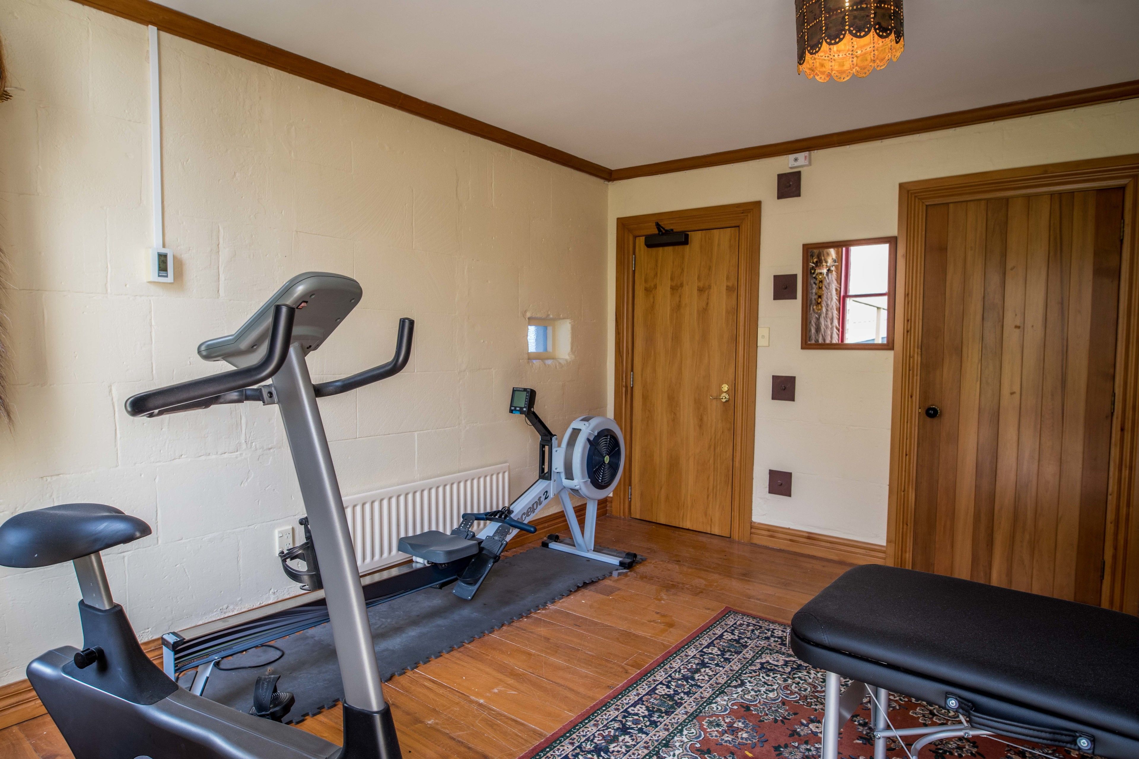 Une pièce comprenant un vélo d’appartement, un banc et une porte.