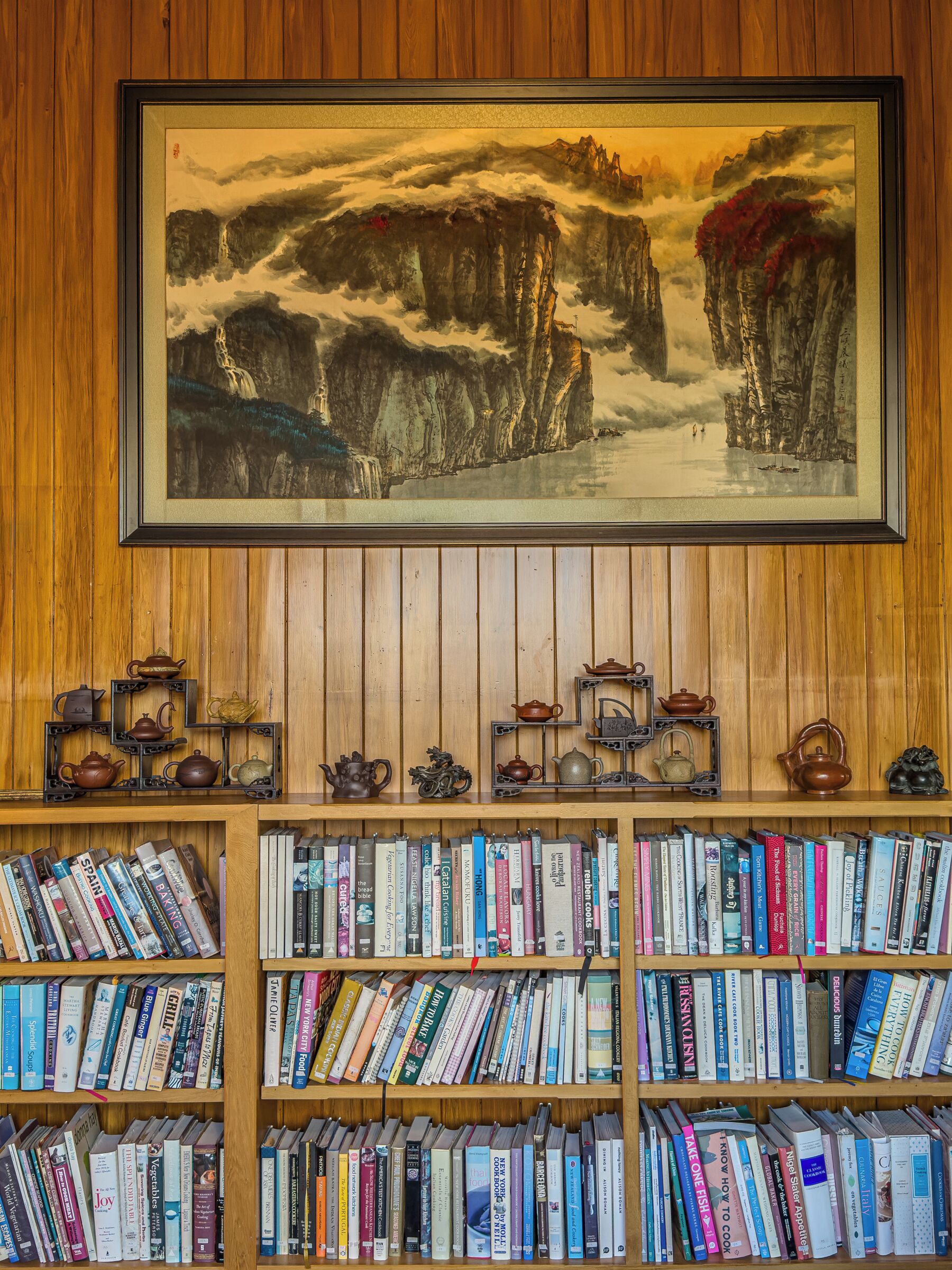 A bookshelf with a framed painting above it.