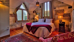 A bedroom with a large bed, a nightstand, a lamp, and a window with curtains. - Pen-y-bryn Lodge (Oamaru)