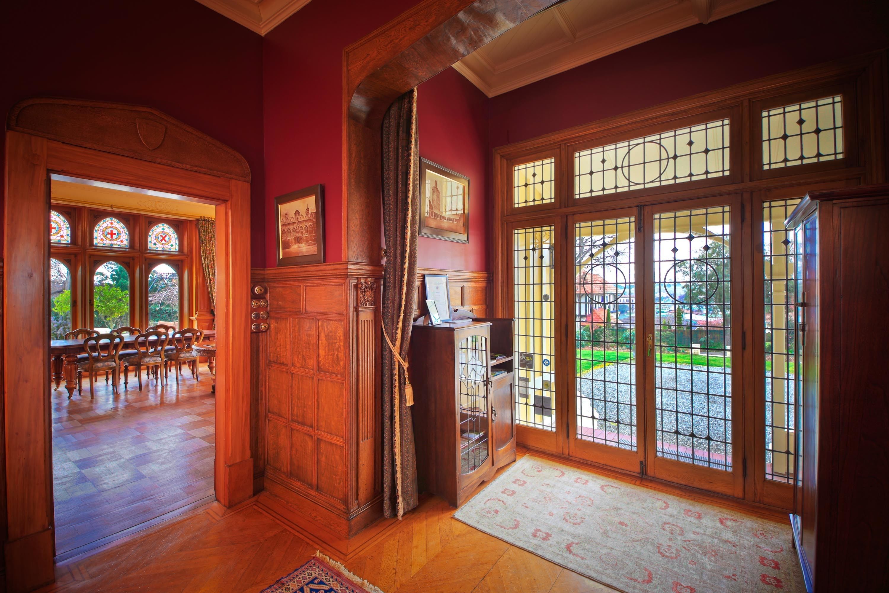 Una habitación con suelo de madera, un comedor con sillas, un armario y ventanas amplias con vistas al exterior.