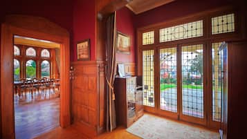 Una habitación con suelo de madera, un comedor con sillas, un armario y ventanas amplias con vistas al exterior.