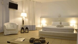 Una habitación de hotel con cama, una silla, escritorio y televisor.