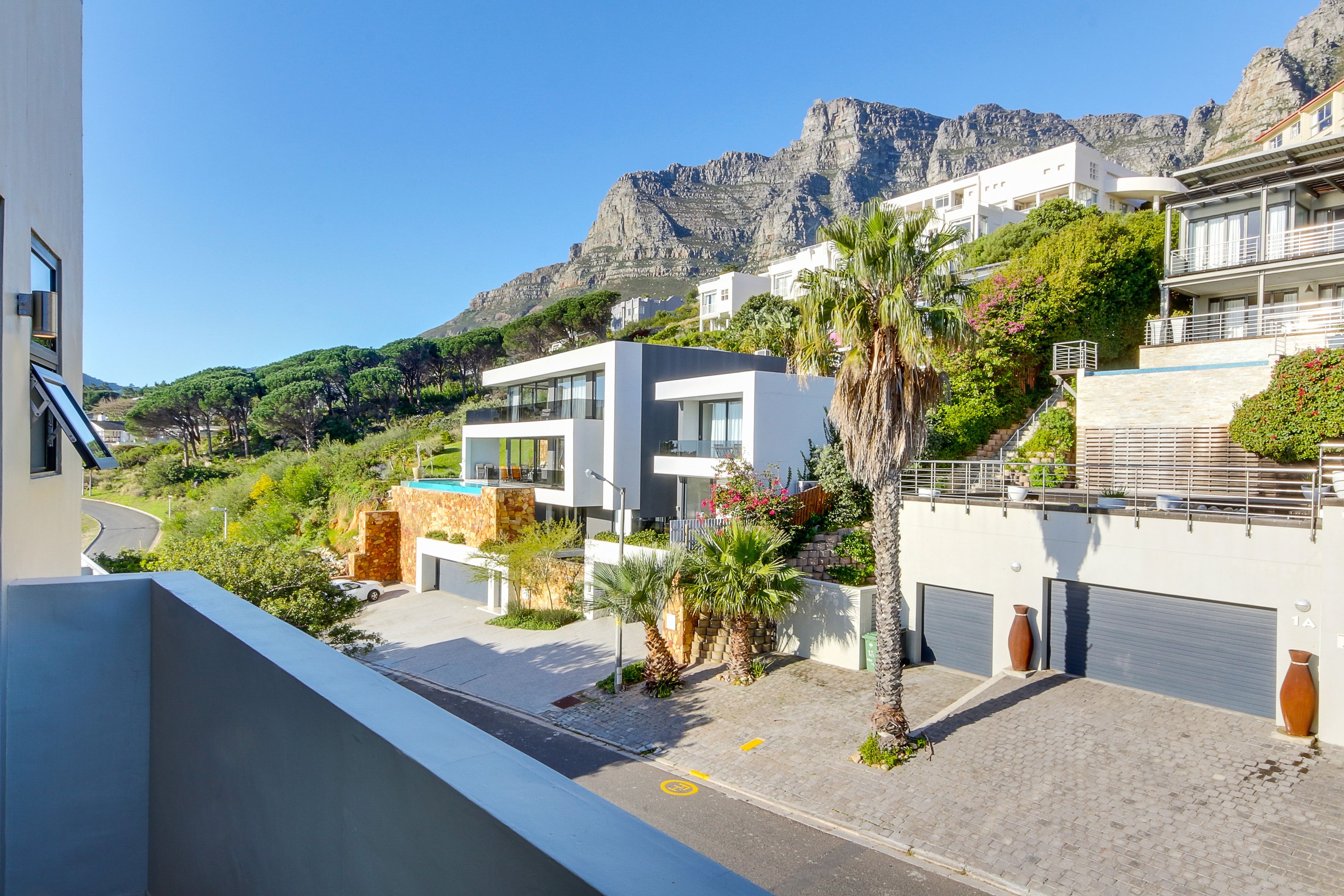 A modern building with a pool, surrounded by greenery and mountains.