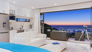 Een moderne slaapkamer met een groot bed, een witte bank, een bijzettafeltje en een balkon met een telescoop.