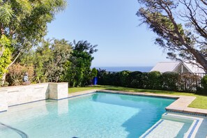 Una piscina al aire libre, sombrillas, sillones reclinables de piscina