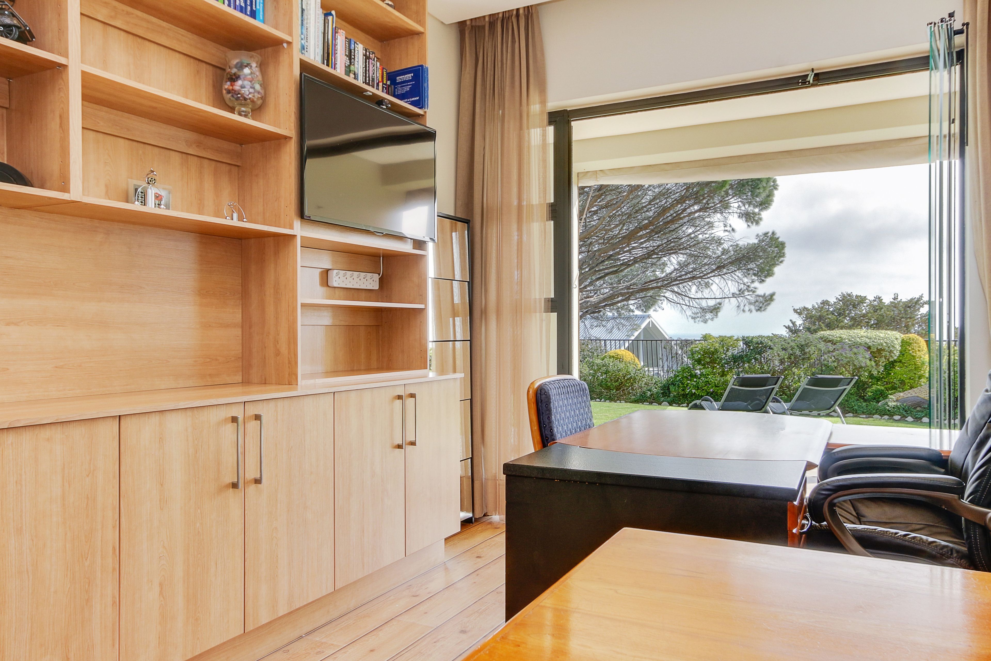 Een moderne keuken met houten kasten, een ingebouwde televisie en een groot raam met uitzicht op de omgeving.