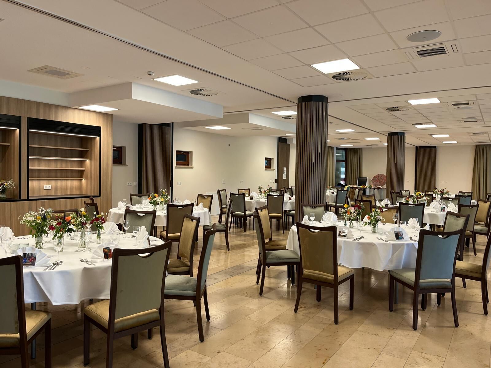 A spacious dining area with round tables, chairs, and a modern ceiling design.