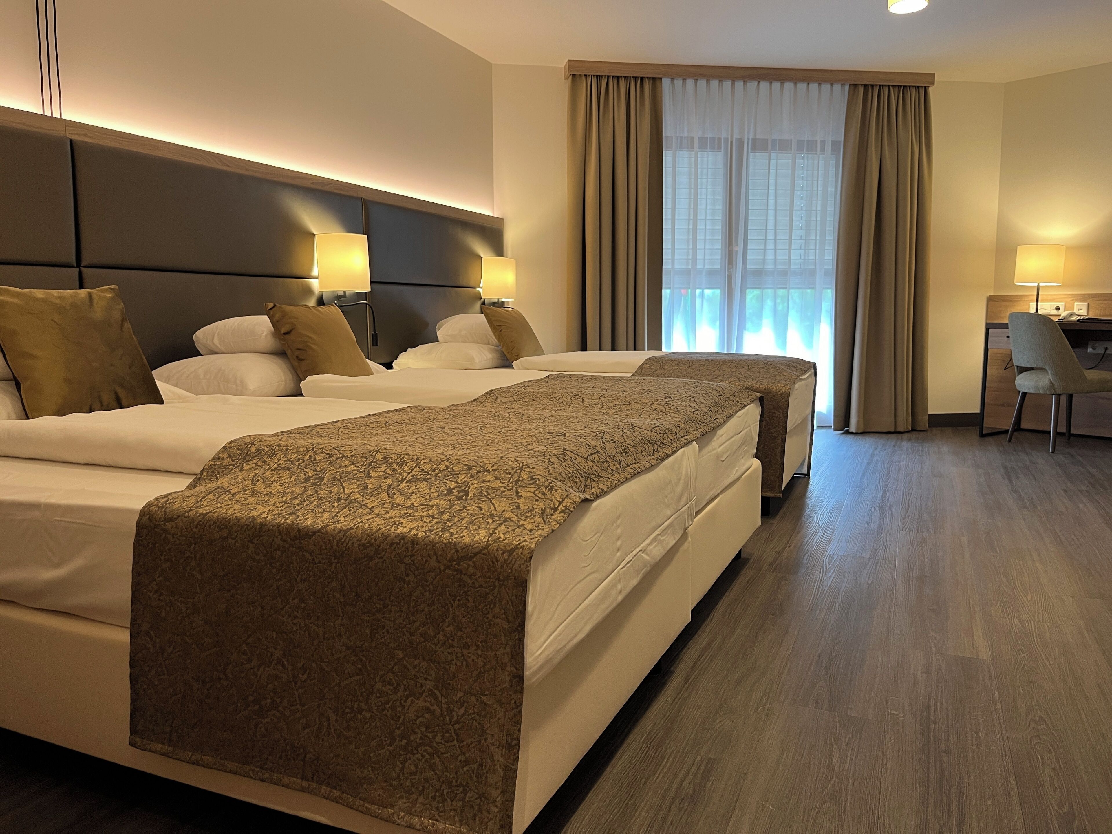Une chambre d’hôtel avec deux lits, un bureau et une chaise.