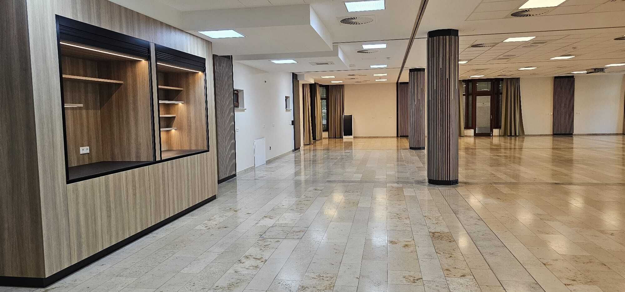 A spacious hallway with a wooden panel wall and a tiled floor.