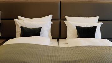 A bed with a brown headboard, white and dark green pillows, and a striped bedspread.