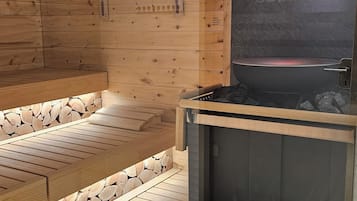 A sauna room with wooden walls, a bench, and a sauna tub.