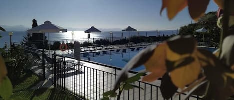 A pool area with umbrellas and a view of the sea.