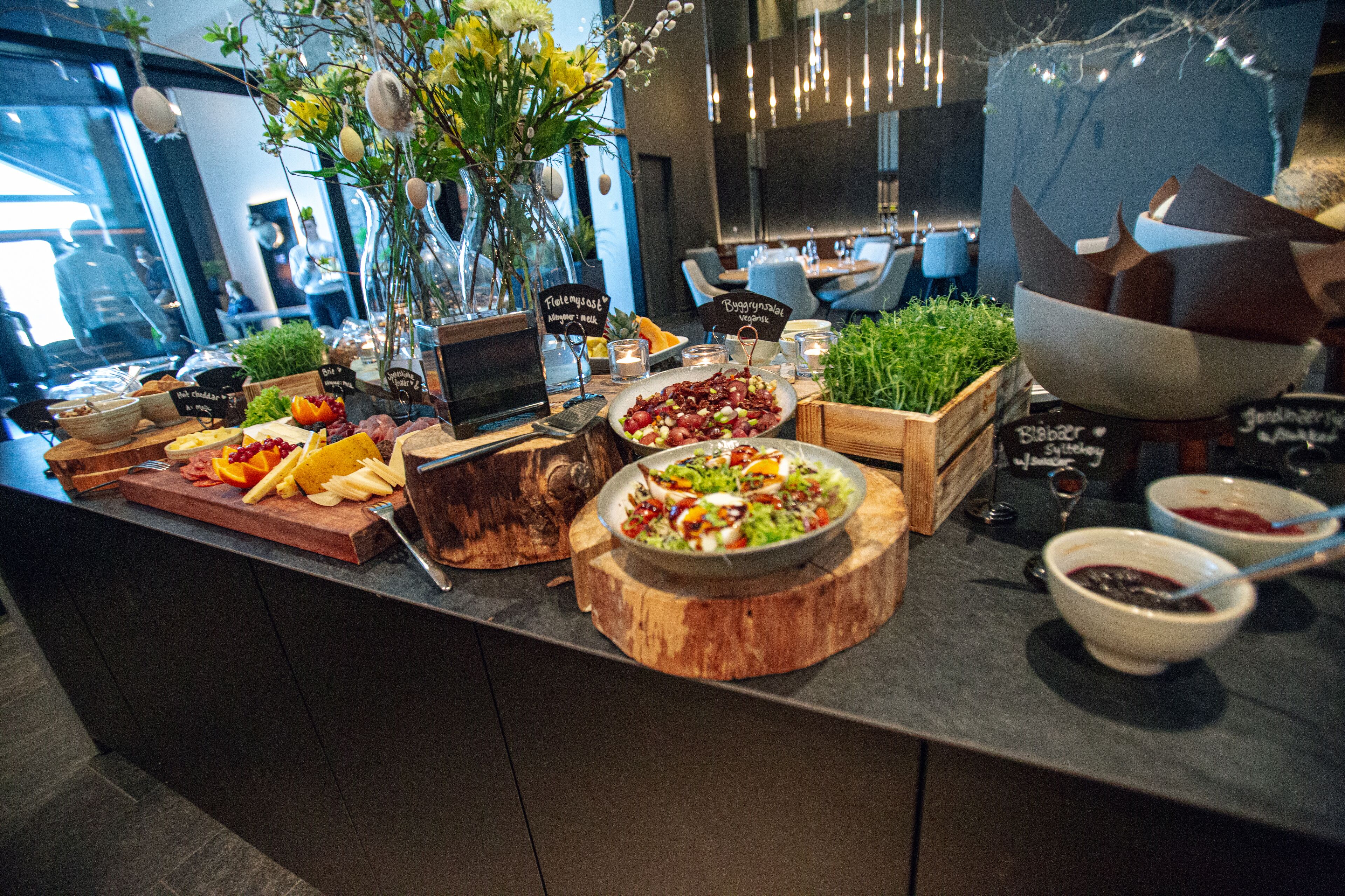 A buffet with various food items and a wooden cutting board.