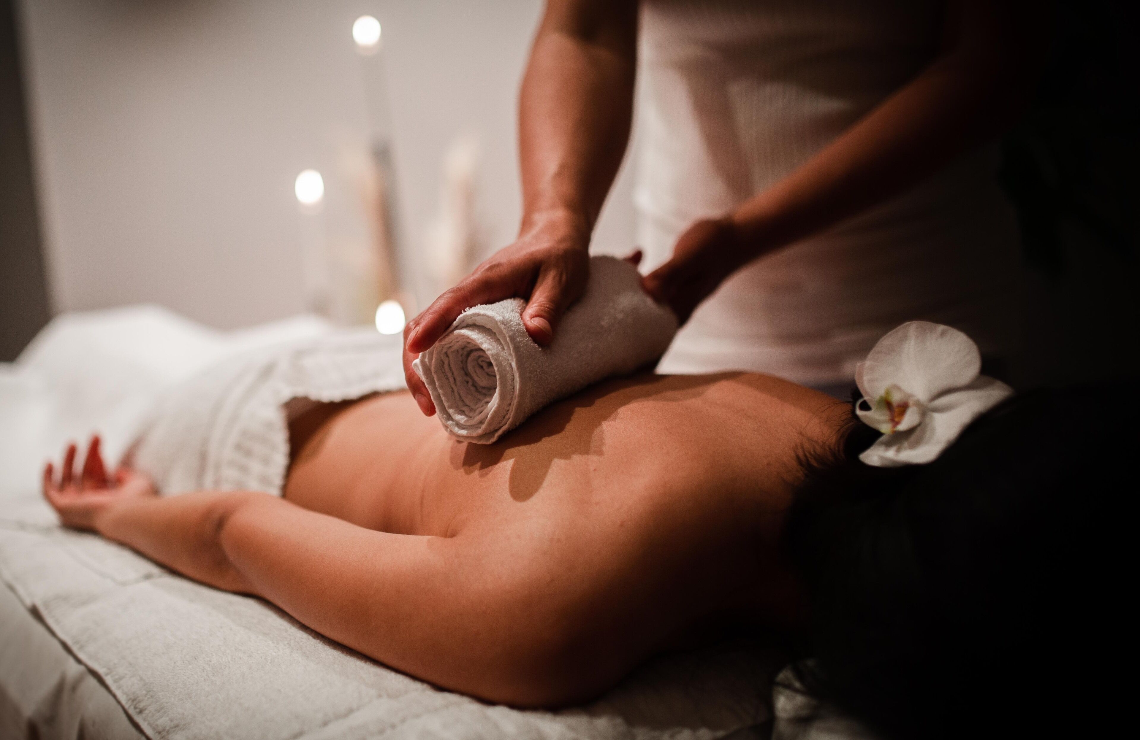 Une personne reçoit un massage avec une serviette enroulée placée dans le dos.