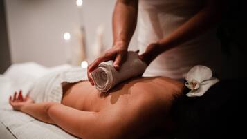 A person receiving a massage with a rolled towel on their back.