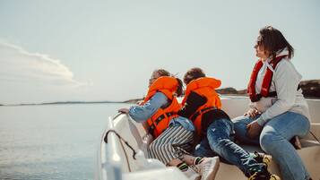 Three people on a boat wearing life jackets.