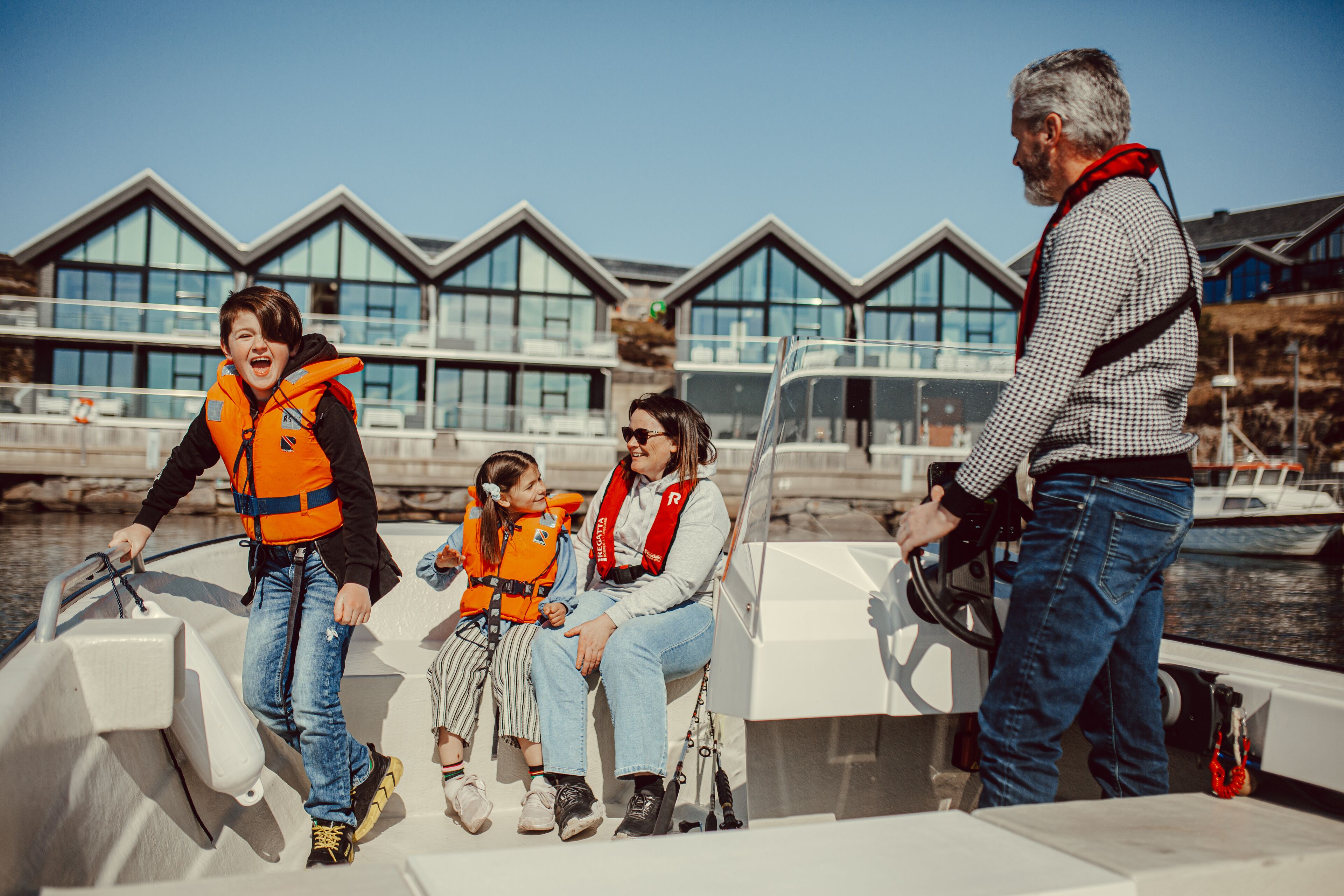 Una familia en un barco, con un edificio moderno al fondo.