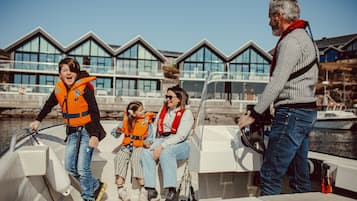 Una familia en un barco, con un edificio moderno al fondo.