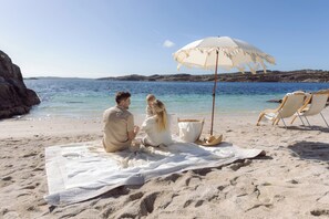 På stranden, hvit sand, strandtelt (mot et tillegg) og kajakkpadling