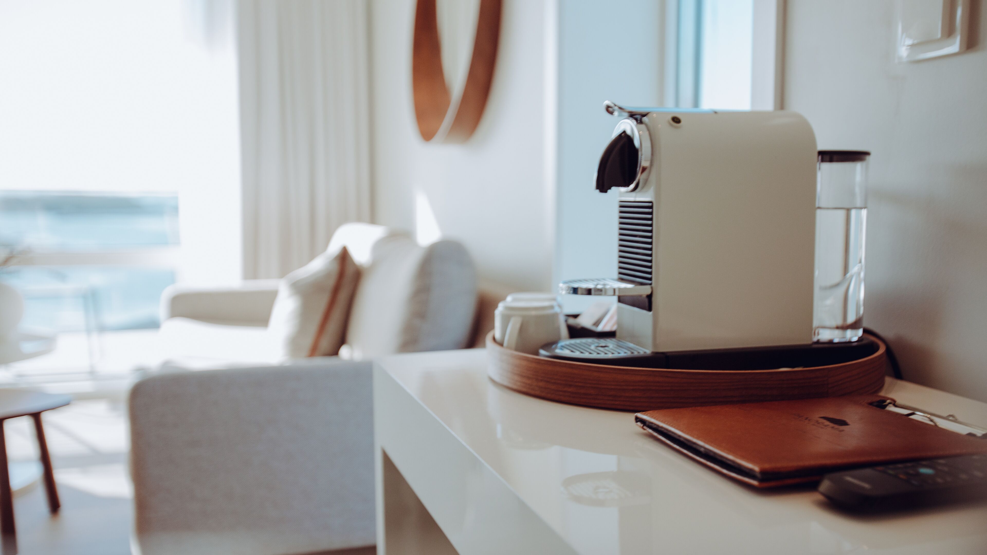 Una habitación de hotel moderna con una cafetera, un control remoto y una libreta de cuero sobre la mesa.