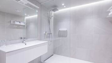A modern bathroom with a glass-enclosed shower, a white sink, and a large mirror.