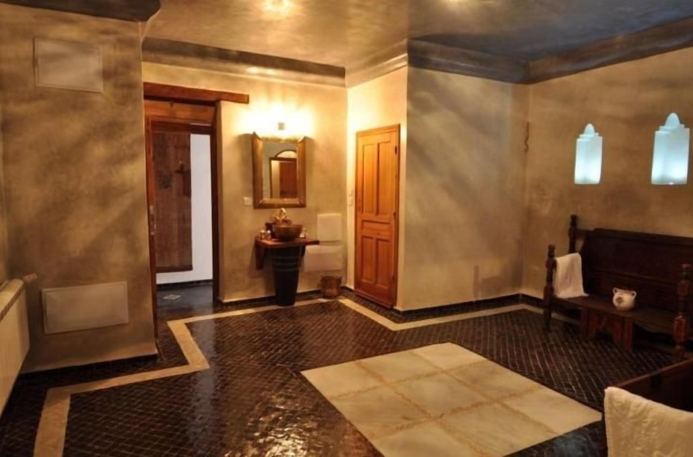 A hallway with a wooden bench, a mirror, and a door.