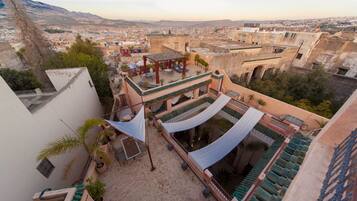 Una terraza en la azotea con pérgola, mobiliario exterior y plantas en macetas.