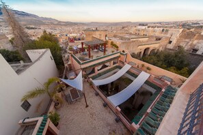 A rooftop terrace with a pergola, outdoor seating, and potted plants.