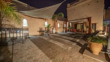 A courtyard with hexagonal tiled flooring, outdoor seating, and potted plants.