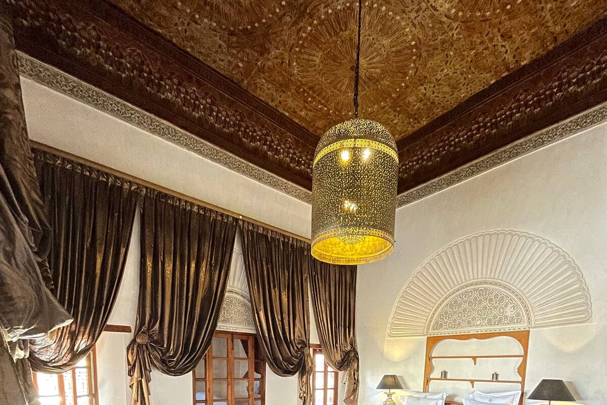 A room with a bed, a sofa, a coffee table, and a chandelier.
