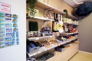 Exposição de produtos no balcão, com prateleiras repletas de itens diversos, incluindo produtos de higiene pessoal e artigos de decoração.