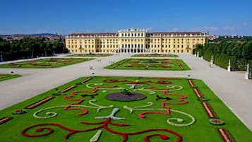 Un edificio grande e histórico con jardines simétricos y una fuente central.