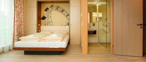 Un dormitorio con cama, alfombra roja, suelo de madera, ducha de vidrio y puerta de madera.