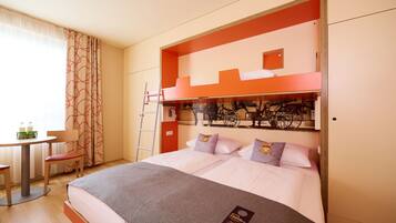 A hotel room with a bunk bed, a desk with a chair, and a window with curtains.