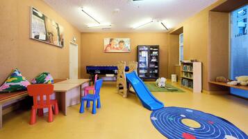 A children's play area with a slide, colorful chairs, and a bookshelf.