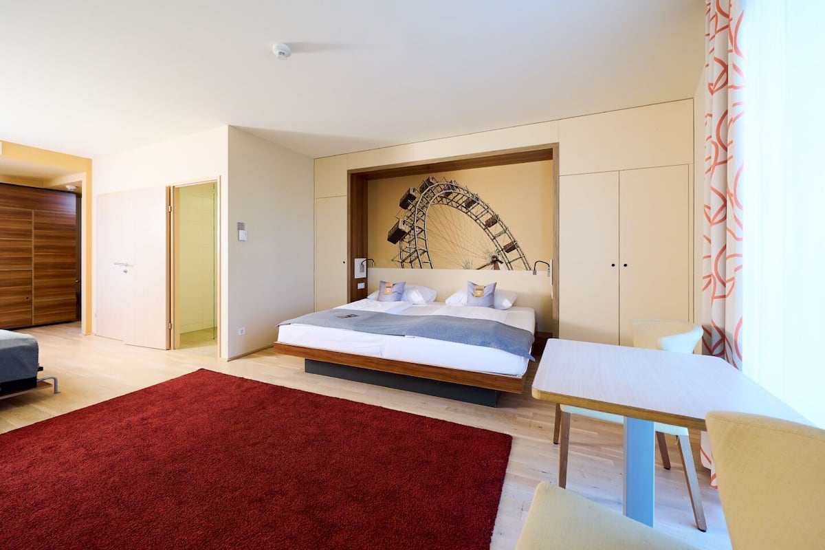 Een moderne slaapkamer met een bed, een bureau en een rood tapijt.