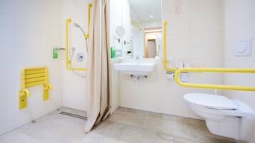 A modern bathroom with a white sink, toilet, and shower area. Yellow grab bars are installed for safety.