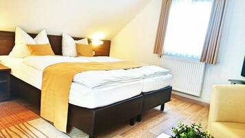 Een moderne hotelkamer met een groot bed, een nachtkastje, een stoel en een raam met gordijnen.
