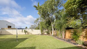 A well-maintained backyard with a lawn, trees, and a wooden fence. - Port Macquarie Motel (Port Macquarie)