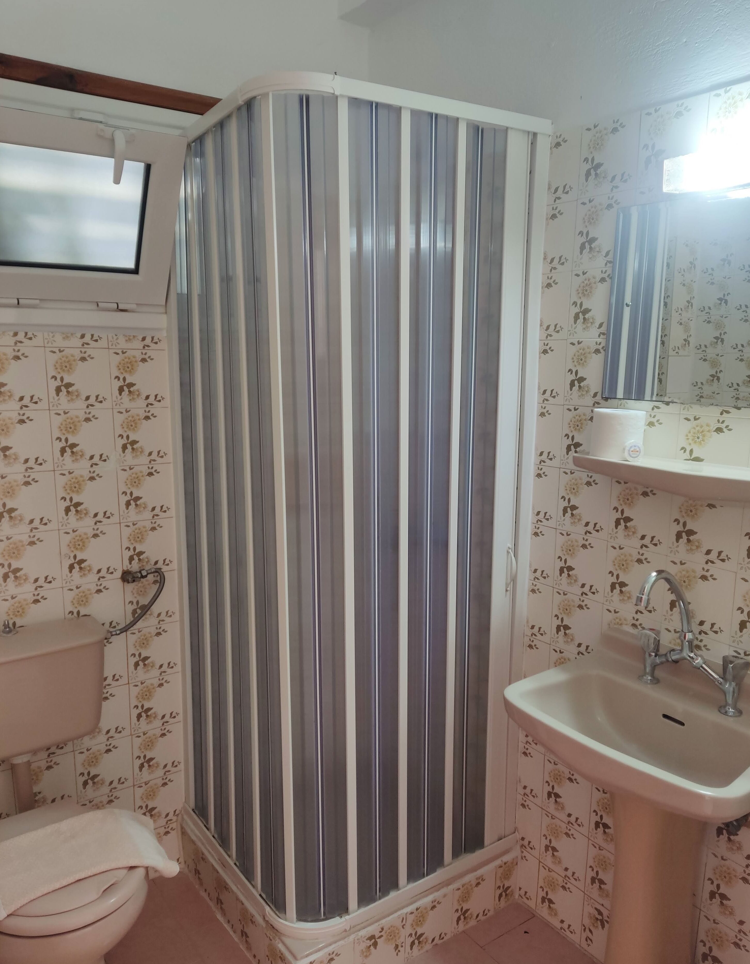 Un baño con cabina de ducha, inodoro, lavabo y un espejo sobre el lavabo.
