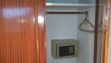 Une porte en bois avec une poignée en métal, une armoire blanche avec une tringle pour suspendre les vêtements, et un four à micro-ondes fixé au mur.