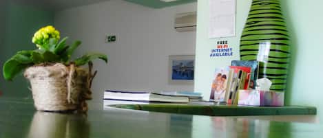 A reception desk with a potted plant, a green vase, and a sign indicating free Wi-Fi.