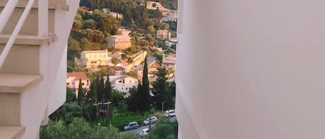 A staircase leading to a balcony with a view of a hillside town.